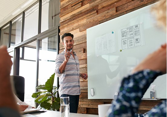 Man standing at whiteboard in group presentation setting