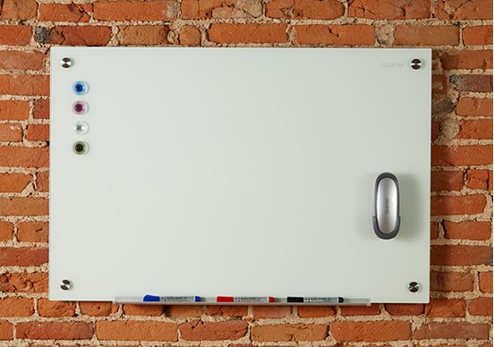 Whiteboard on brick background with markers, eraser, and magnets on board