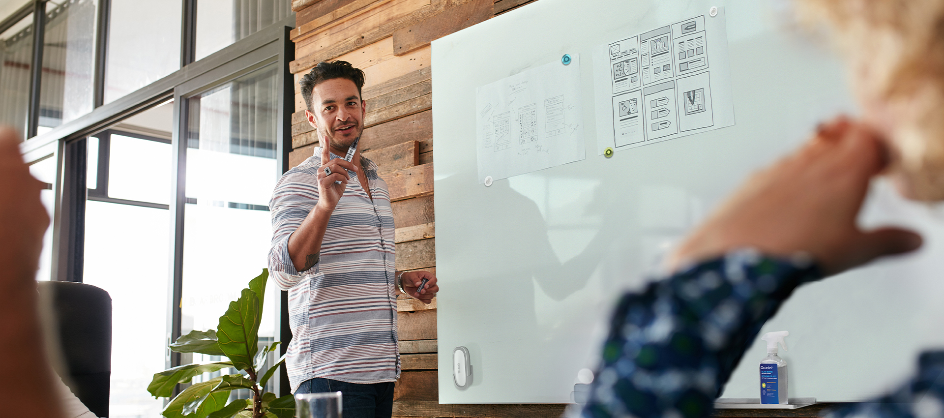 Man running a meeting while writing  on a Quartet glassboard