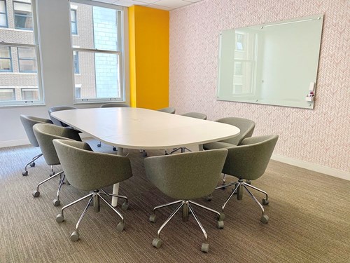A conference room setting with a Quartet Infinity® Glass Dry-Erase Board mounted on the wall.