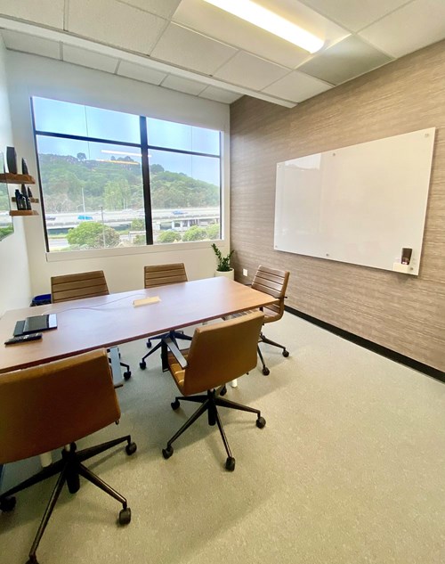 A conference room setting with a Quartet® Brilliance Glass Dry-Erase Board mounted on the wall