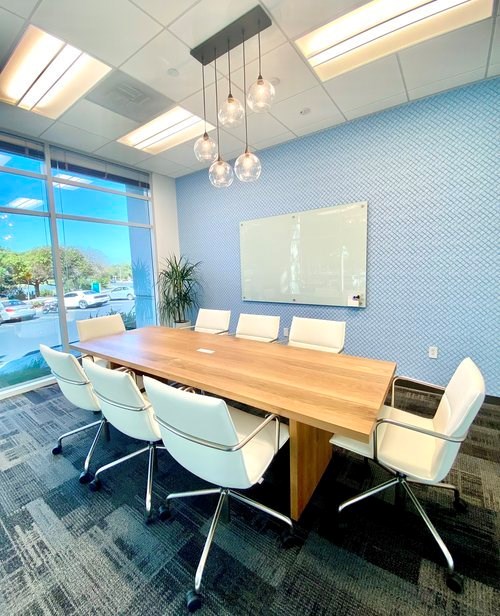 A conference room with a Quartet® Infinity® Glass Dry-Erase Board mounted to the wall.