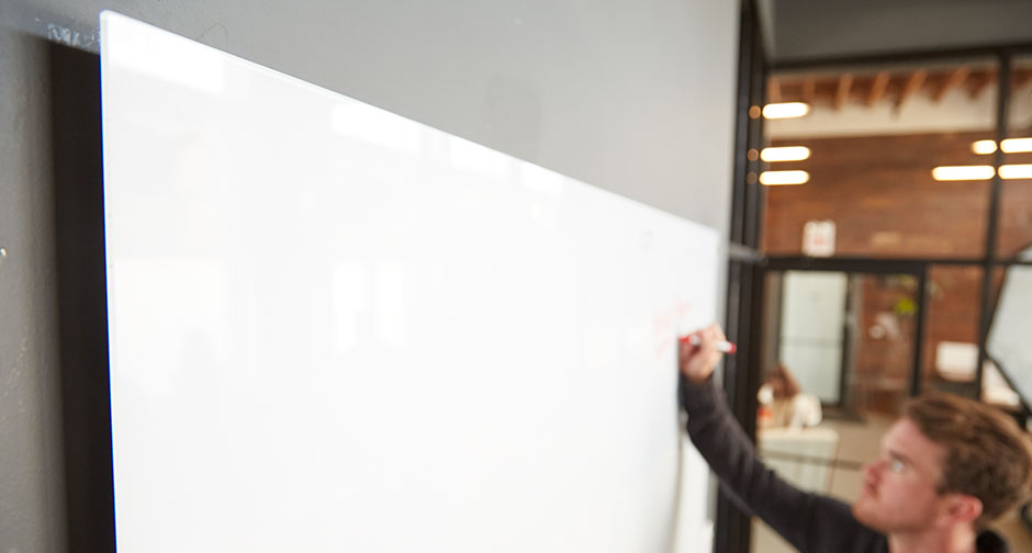 Person writing an idea on a glassboard